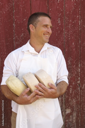 Photo: Cheese Maker in Apron Holding Goat Cheese Rounds Cheese Maker in Apron Holding Goat Cheese Rounds