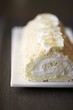 Rolled Sponge Cake with Cream Filling and Toasted Coconut on a White Platter