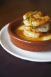 Shrimp and Grits in a Brown Dish with Chive Garnish