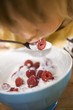 Small child eating yoghurt with fresh raspberries
