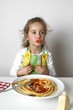 Foto: Girl eating macaroni with tomato sauce Girl eating macaroni with tomato sauce