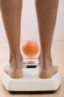 Young woman on bathroom scales with orange