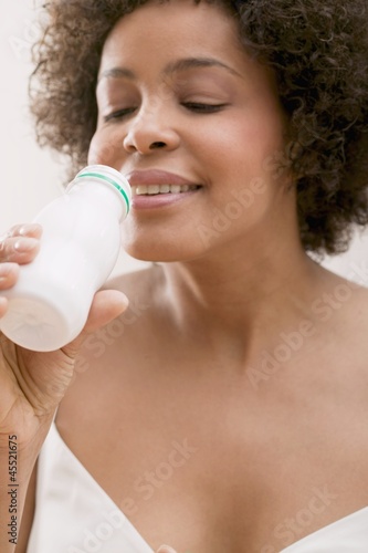 Photo: Young woman drinking milk drink out of a plastic bottle Young woman drinking milk drink out of a plastic bottle