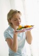 Woman smelling grilled vegetables on plate