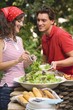 Young woman serving green salad at a barbecue