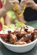 Photo: Grilled chicken wings, men with beer in background Grilled chicken wings, men with beer in background
