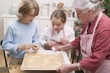 Grandmother showing grandchildren baking tray of Xmas biscuits