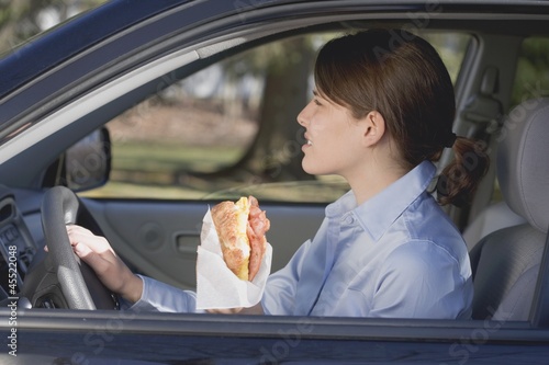 Photo: Young woman eating croissant in car Young woman eating croissant in car