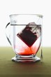 Red Tea Bag Steeping in Glass Mug