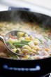 Steaming vegetable soup in pot with ladle (close-up)
