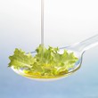 Oil running onto lettuce leaf on spoon