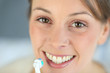 Closeup on woman's toothy smile brushing her teeth