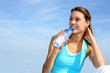 Thirsty fitness girl holding bottle of water