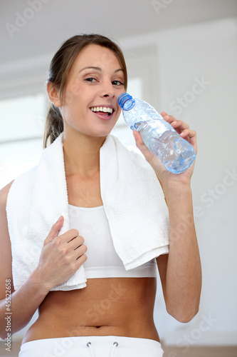 Photo: Cheerful fitness girl drinking water after exercising Cheerful fitness girl drinking water after exercising