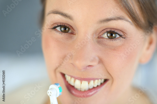 Photo: Closeup on woman's toothy smile brushing her teeth Closeup on woman's toothy smile brushing her teeth