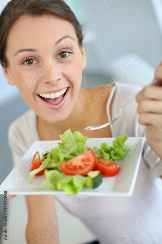 Photo: Closeup of cheerful woman eating fresh salad Closeup of cheerful woman eating fresh salad