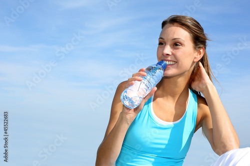 Photo: Thirsty fitness girl holding bottle of water Thirsty fitness girl holding bottle of water
