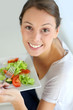 Closeup of cheerful woman eating fresh salad