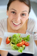 Closeup of cheerful woman eating fresh salad