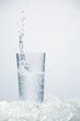 Ice cube falling into glass of ouzo