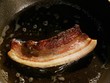 Frying a slice of pancetta (cured pork belly) in oil