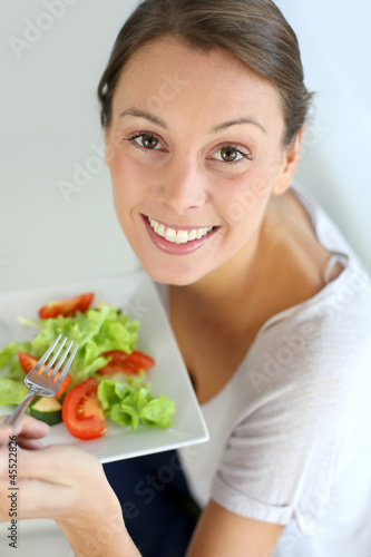 Photo: Closeup of cheerful woman eating fresh salad Closeup of cheerful woman eating fresh salad