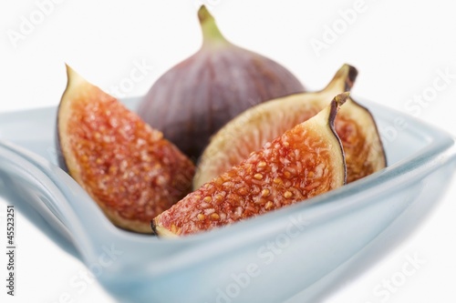 Photo: Fresh figs (whole, halved and quartered) in blue glass bowl Fresh figs (whole, halved and quartered) in blue glass bowl
