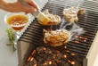 Chops on a grill being brushed with apricot sauce