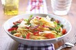 Spaghetti Tossed with Fresh Vegetables in a White Bowl with a Fork