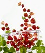 Many strawberries falling into a glass bowl