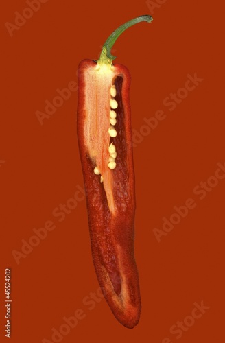 Photo: Half a red chilli pepper on a red surface Half a red chilli pepper on a red surface
