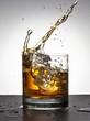 Ice cube falling into whisky glass