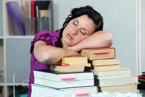 Photo: Overworked woman sleeping on a stack of books Overworked woman sleeping on a stack of books