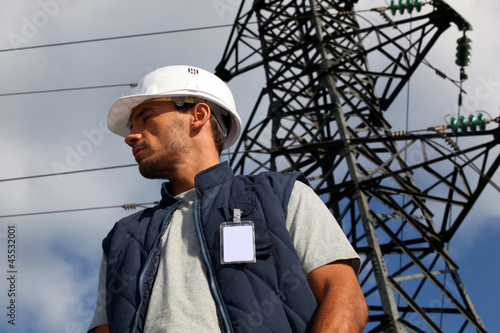 Photo: Worker standing in front of an electricity pylon Worker standing in front of an electricity pylon