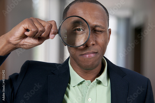 Photo: Black Man Looking through a magnifying glass Black Man Looking through a magnifying glass