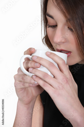 Photo: A brunette drinking coffee. A brunette drinking coffee.