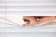 Woman peering through blinds