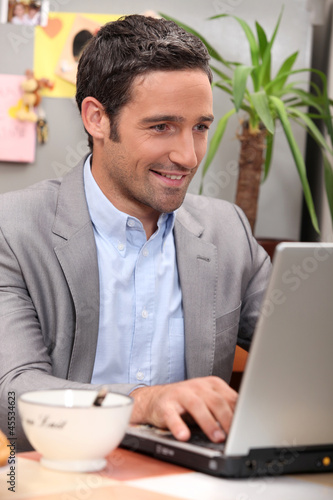 Photo: Man using his laptop during breakfast Man using his laptop during breakfast