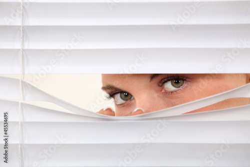 Photo: Woman peering through blinds Woman peering through blinds