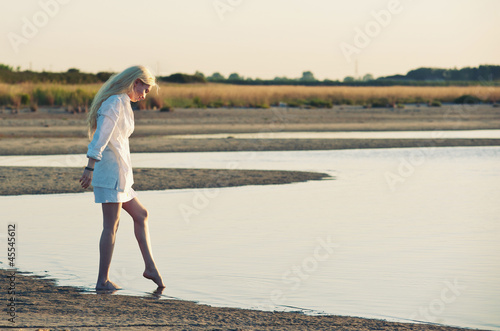 Photo: Beautiful young woman at the beach at sunset. Beautiful young woman at the beach at sunset.