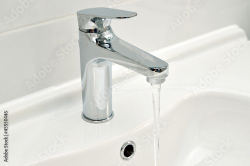 Photo: A tap on a bathroom sink against a white wall. A tap on a bathroom sink against a white wall.