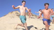 Group Of Teenagers Running Down Sand Dunes