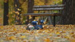 The boy is throwing autumn leaves and runs away
