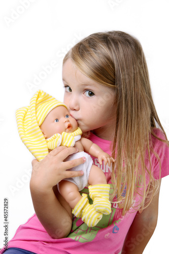 Photo: Bambina seduta che bacia un bambolotto Bambina seduta che bacia un bambolotto
