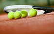 Close up of tennis racquet and balls on the clay tennis court
