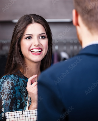 Photo: Smiling girl with long dark hair talks to shop assistant Smiling girl with long dark hair talks to shop assistant