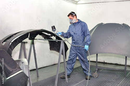 Photo: Worker painting car parts. Worker painting car parts.