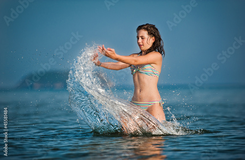 Photo: Young teen girl playing with waves at the beach. Young teen girl playing with waves at the beach.