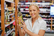 Frau beim Weinregal eines Supermarktes