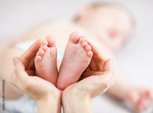 Photo: mother hands holding small baby's feet mother hands holding small baby's feet